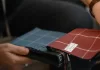 Jak skutecznie zamawiać materiały tekstylne do firmy – krok po kroku Osoba trzyma próbnik tkanin w kratę, oglądając różne kolory.