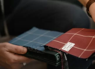 Jak skutecznie zamawiać materiały tekstylne do firmy – krok po kroku Osoba trzyma próbnik tkanin w kratę, oglądając różne kolory.