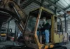 Przeglądy maszyn budowlanych — harmonogram, który realnie ogranicza przestoje Mechanik w hali serwisowej wykonuje przegląd zużytej koparki gąsienicowej.